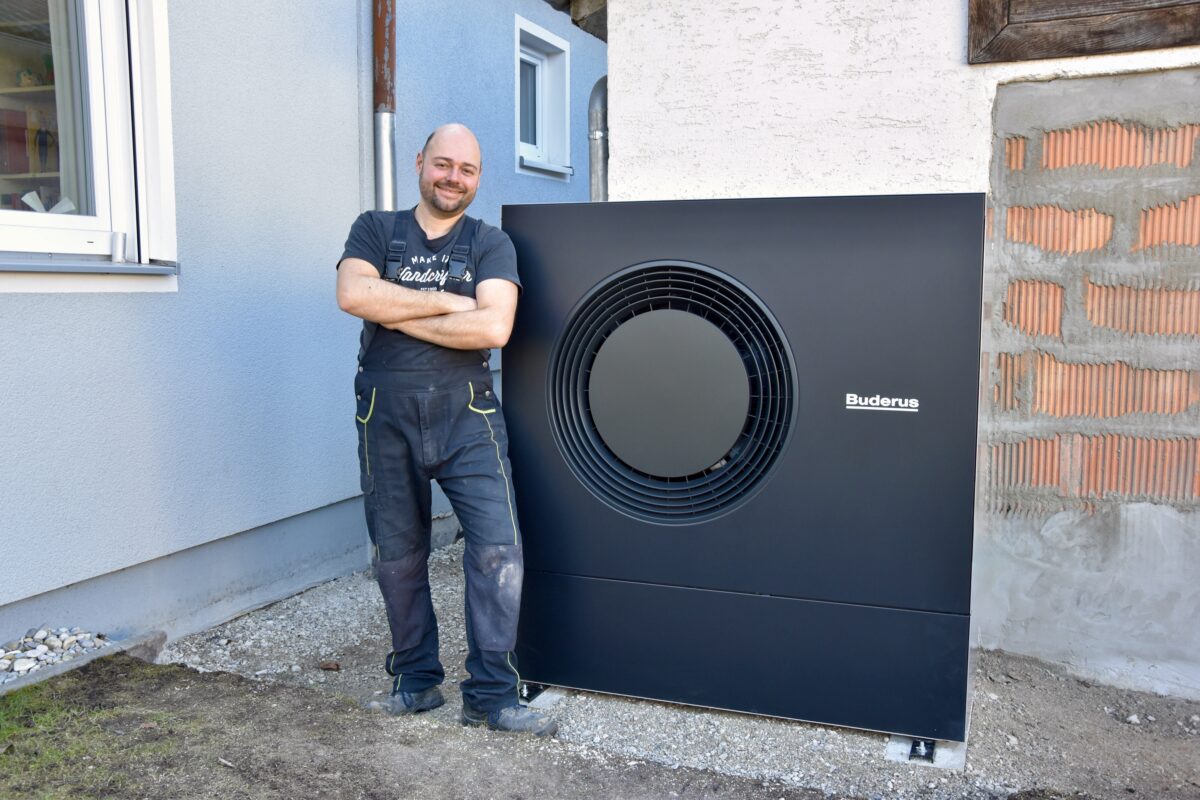 Ein zufriedener Selbstbauer neben seiner fertig aufgestellten Wärmepumpe